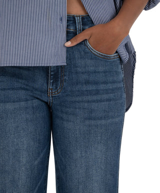 Person wearing blue jeans and a striped shirt with a beige background