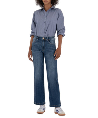 Person wearing a blue striped shirt and jeans on a beige background
