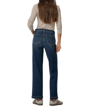 Person wearing blue jeans and a beige top on a white background