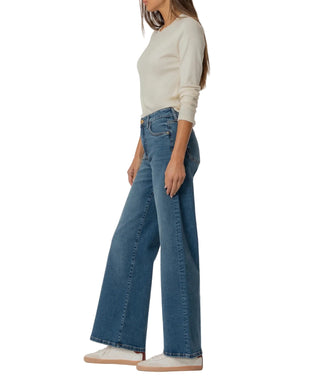 Person wearing blue jeans and a white top on a plain background