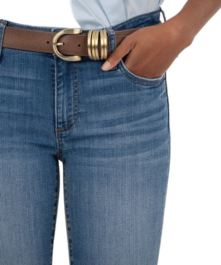 Close-up of blue jeans with a brown belt and gold buckle on a beige background
