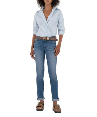 Person wearing a light blue shirt and jeans on a beige background