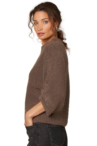 Woman wearing a brown sweater against a beige background