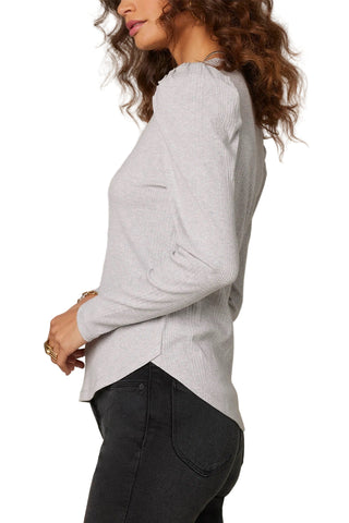 Person wearing a light gray sweater and black pants against a beige background