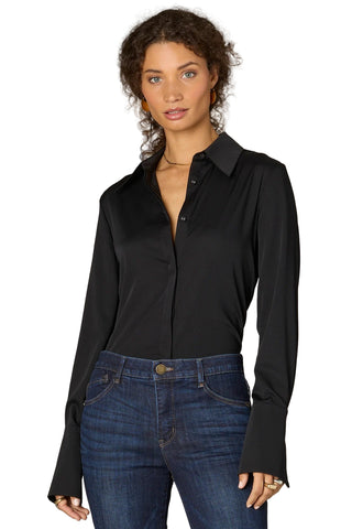 Woman wearing a black shirt and blue jeans against a neutral background
