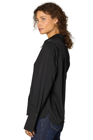 Woman wearing a black shirt and blue jeans against a beige background