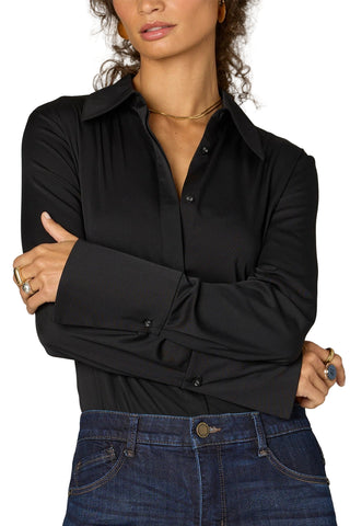 Person wearing a black shirt and blue jeans with a neutral background