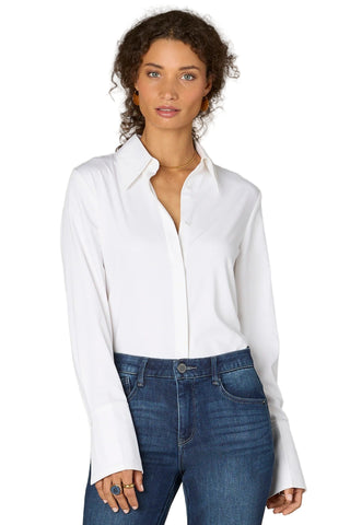 Woman wearing a white shirt and blue jeans against a neutral background