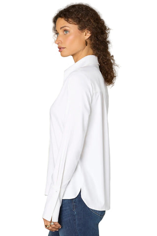 Woman wearing a white blouse and blue jeans against a plain background
