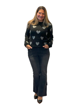 Woman wearing a black sweater with heart patterns in front of an 'Anne's on the Avenue' sign.