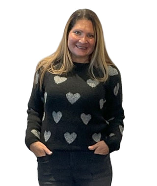 Woman wearing a black sweater with heart patterns against a white background