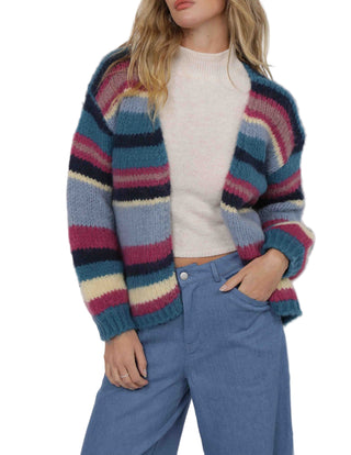 Person wearing a colorful striped sweater and blue pants on a white background