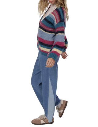 Person wearing a colorful striped sweater and blue pants on a white background