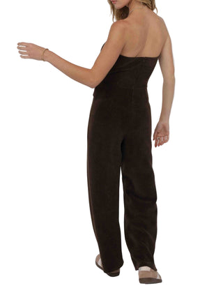 Woman wearing a brown strapless jumpsuit against a white background
