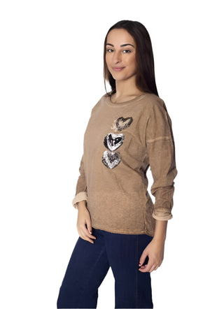 Woman wearing a brown sweater with heart designs on a white background