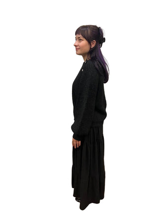 Person wearing a black outfit standing in front of a mirror.