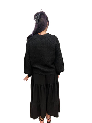 Person wearing a black outfit standing in front of a mirror.