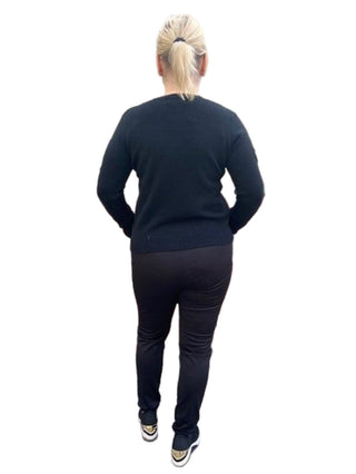 Person wearing a black outfit standing against a brick wall.