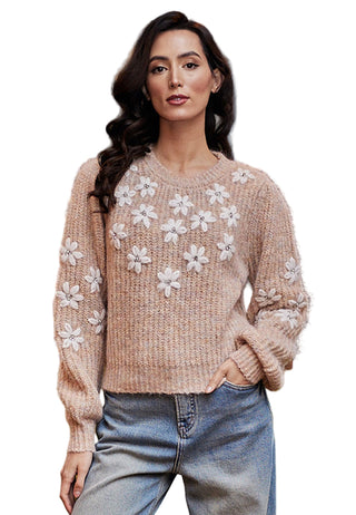 Woman wearing a beige sweater with floral patterns sitting on a green couch.