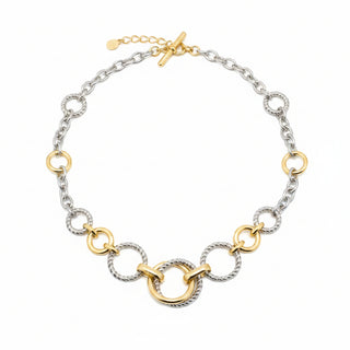 A two-tone chain link choker necklace with gold and silver metal rings, displayed on a light beige surface.