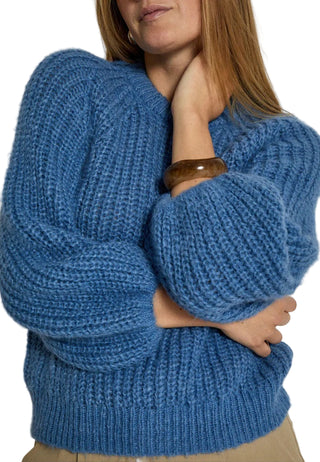 Person wearing a blue knitted sweater on a plain background