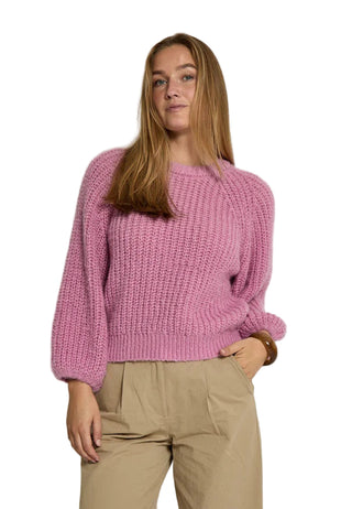 Person wearing a pink knitted sweater against a white background