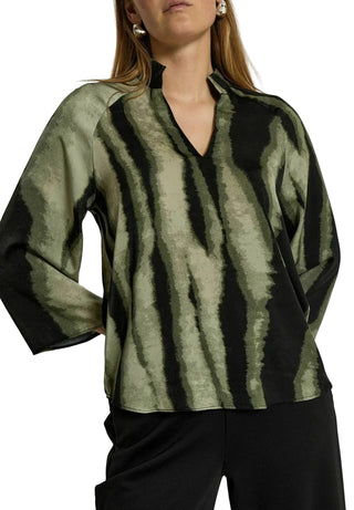 Woman wearing a green and black patterned blouse against a white background