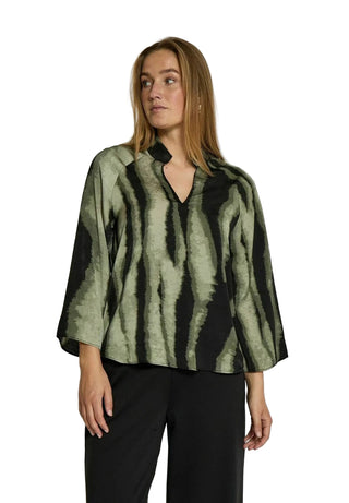 Woman wearing a green and black patterned blouse against a white background