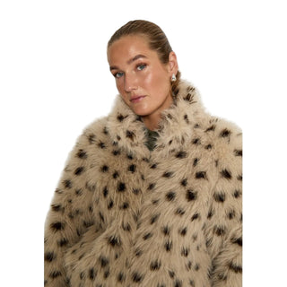 Woman wearing a beige fur coat with black spots on a white background