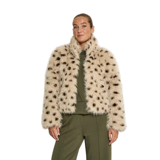 Woman wearing a beige fur coat with black spots on a white background