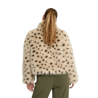 Person wearing a fluffy beige jacket with black spots on a white background