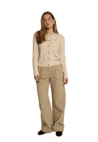 Woman wearing a beige cardigan and pants on a white background