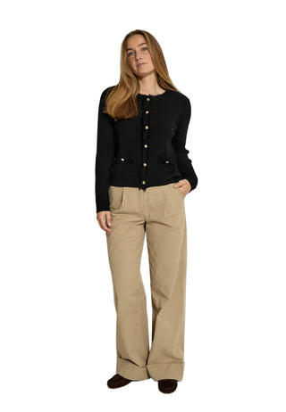 Woman wearing a black cardigan and beige pants on a white background