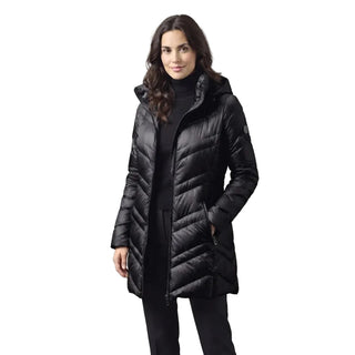 A woman wearing a black hooded puffer jacket with a chevron quilted pattern, styled over a black turtleneck and black pants, set against a solid gray studio background.
