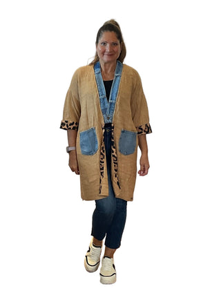 Woman wearing a beige cardigan with denim accents on a white background