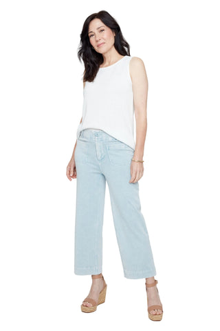 Woman wearing a white sleeveless top and light blue jeans on a white background