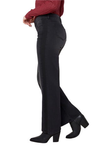Person wearing black flared pants and black shoes on a white background