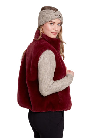 Woman wearing a red fur vest and beige headband on a white background