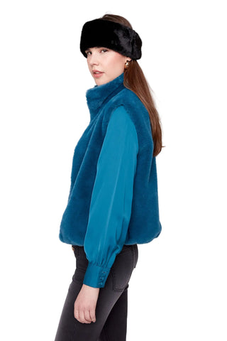 Woman wearing a teal fleece jacket and black fur headband on a white background