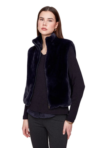 Woman wearing a black fur vest over a dark top on a white background