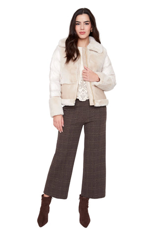 Woman wearing a cream jacket, white top, and brown plaid pants on a white background
