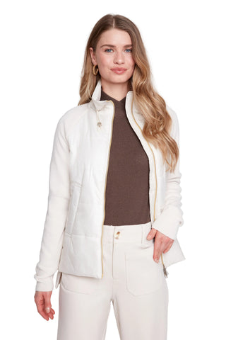 Woman wearing a white jacket over a brown shirt with a plain background