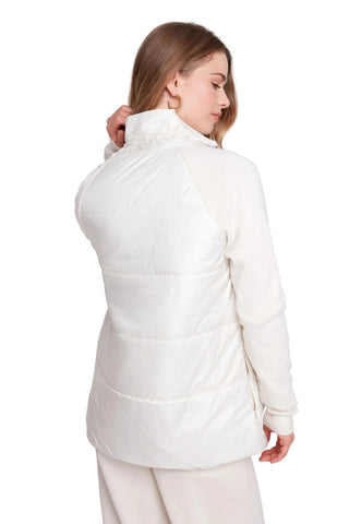 Woman wearing a white quilted jacket on a plain background