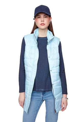 Person wearing a light blue puffer vest over a dark blue shirt with jeans on a plain background