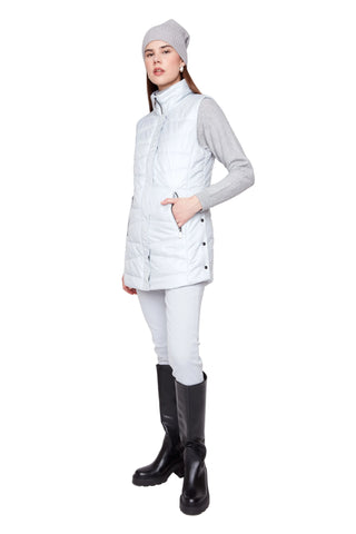 Person wearing a white puffer vest, gray shirt, white pants, and black boots on a white background