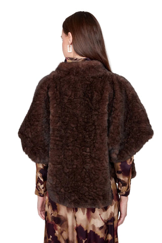 Woman wearing a brown fur coat with a plain background