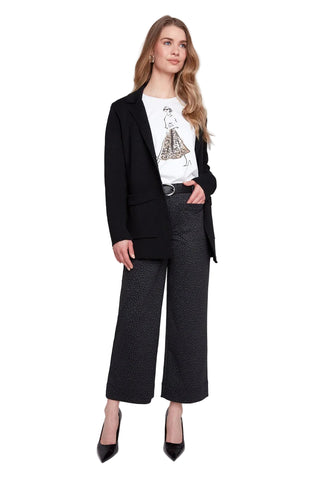 Woman wearing a black blazer, white shirt with graphic design, and black patterned pants on a white background