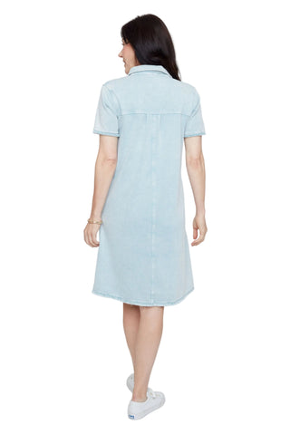 Woman wearing a light blue denim dress against a white background