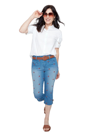 Woman wearing a white shirt and blue jeans with red floral patterns on a white background