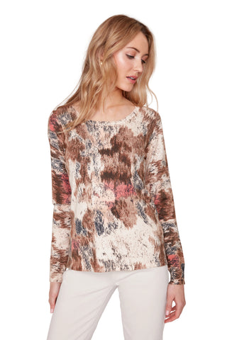Woman wearing a patterned long-sleeve top against a white background